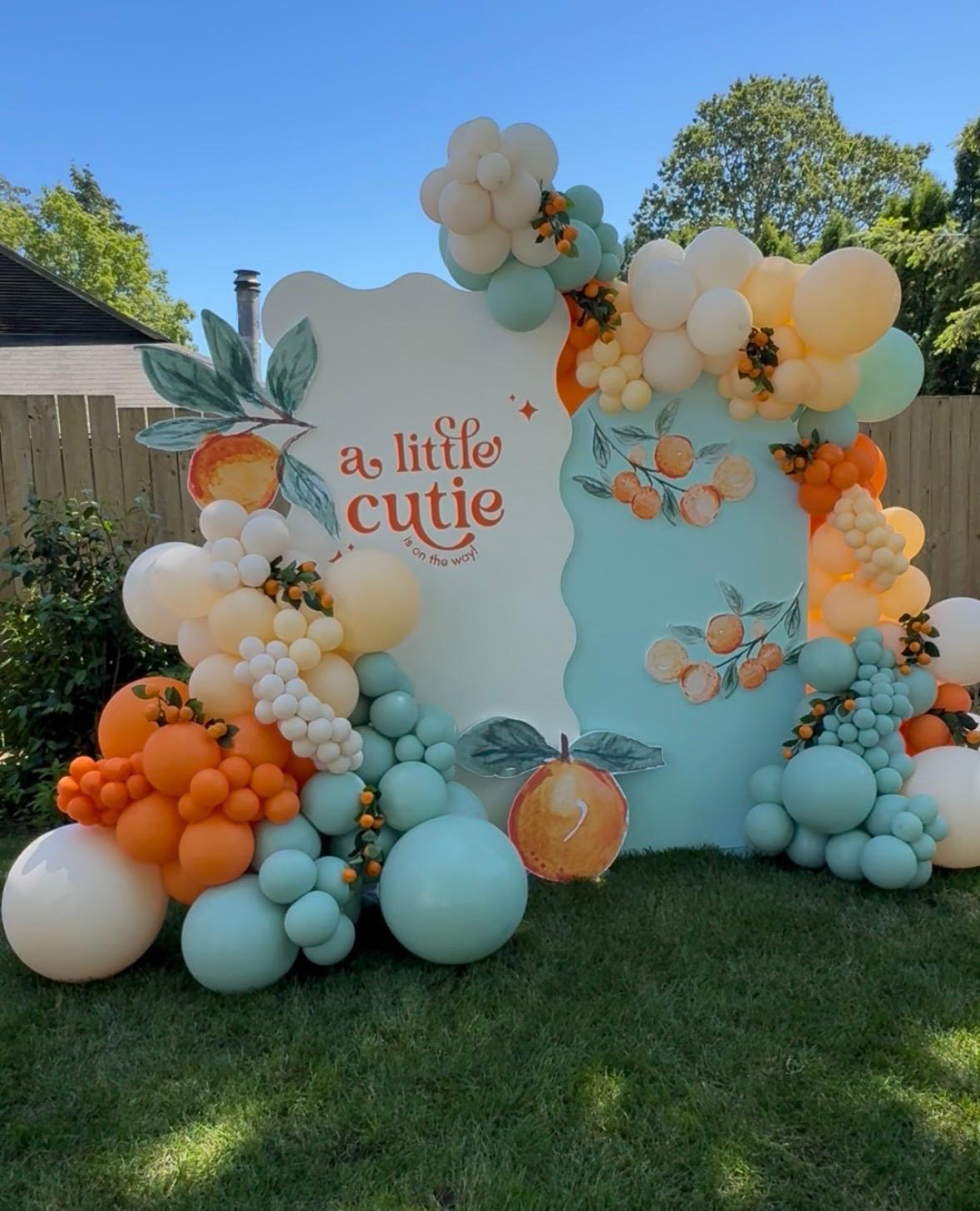 A Little Cutie Magic Hour backdrop with peach and blue balloons